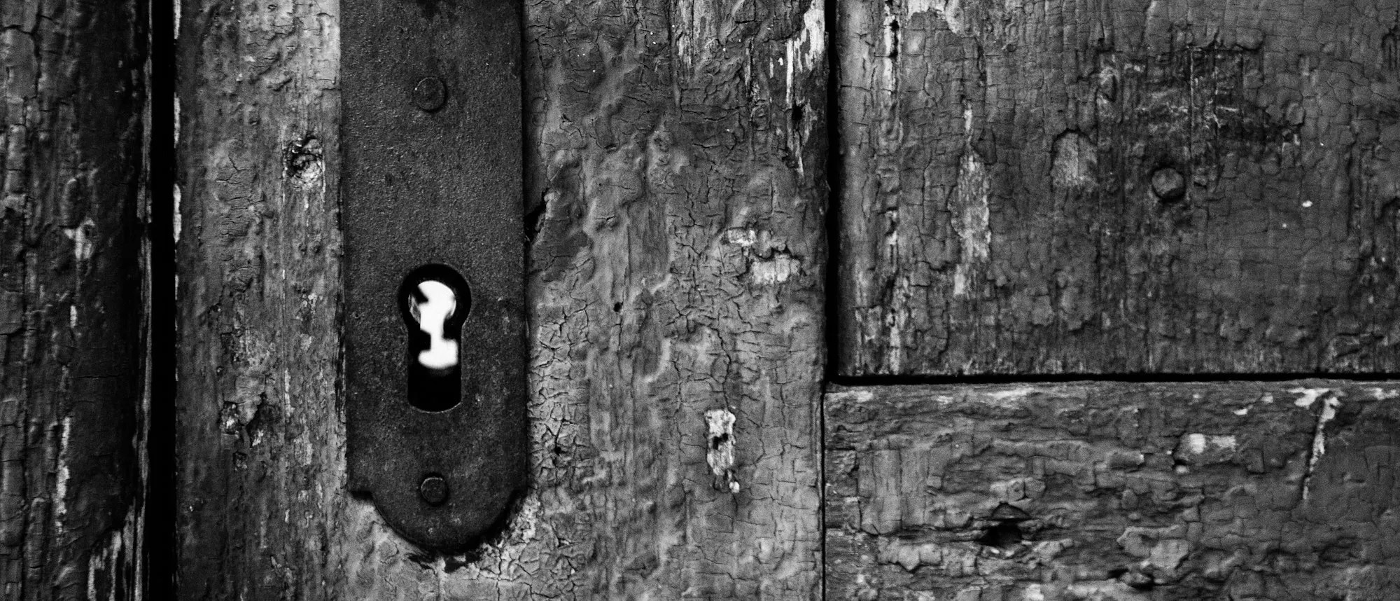 Une serrure ancienne sur une porte en bois, en noir et blanc